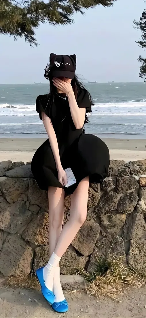 黑裙美女手机壁纸｜海边石滩背景图片 - 休闲穿搭「哲风壁纸」
