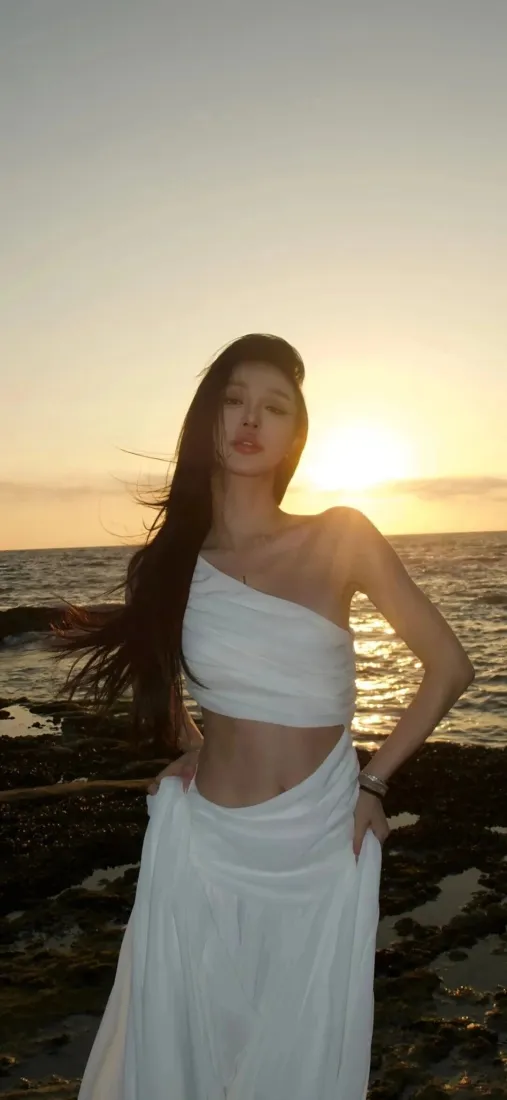 海边长发美女手机壁纸｜黄昏礁石海岸背景图片 - 白裙氛围感人像「哲风壁纸」