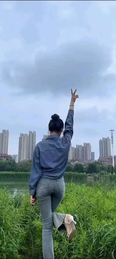 蓝衣美女背影手机壁纸｜河畔草地背景图片 - 城市高楼阴天户外随拍「哲风壁纸」